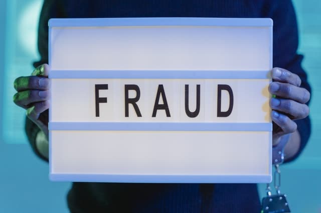Person holding sign that says fraud 