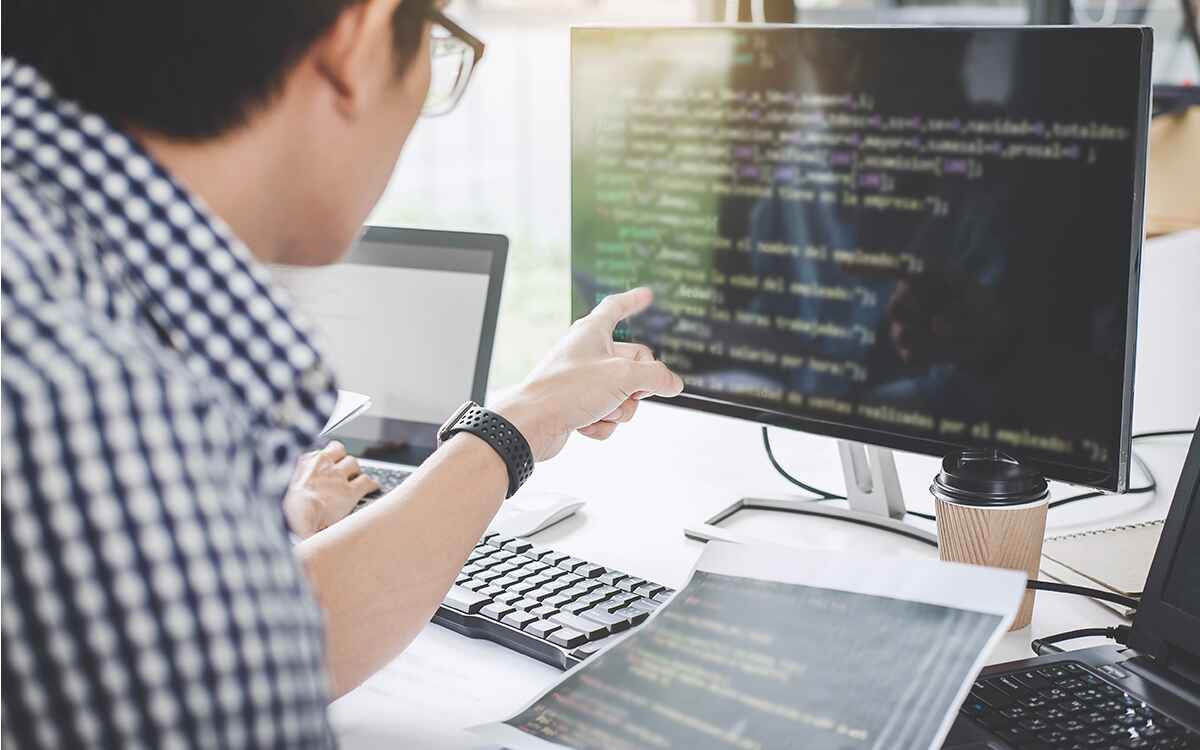 Writing codes and typing data code technology, Programmer cooperating working on web site project in a software developing on desktop computer at company
