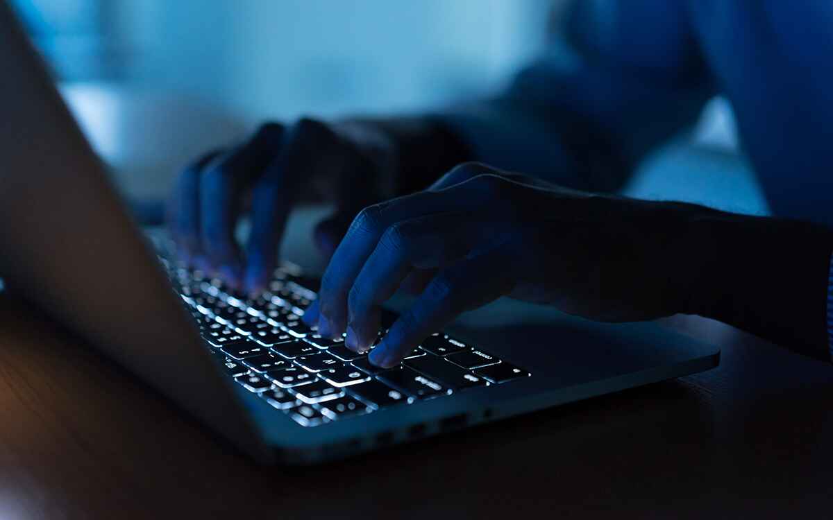Close up programmer man hand typing on keyboard laptop for register data system or access password at dark operation room , cyber security concept