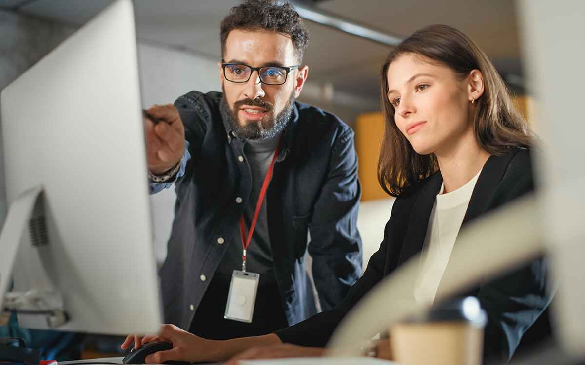 Lecturer Helps Scholar with Project, Advising on Their Work. Teacher Giving Lesson to Diverse Multiethnic Group of Female and Male Students in College Room, Teaching New Academic Skills on a Computer.