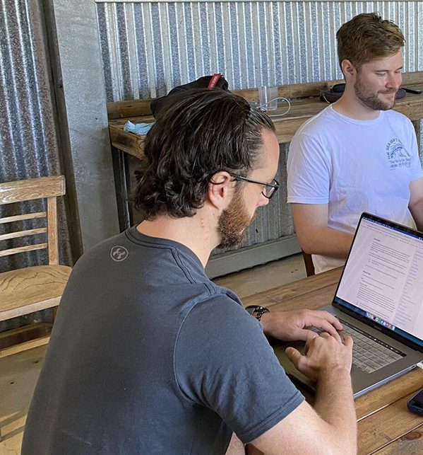 Make an impact A group of men sitting at a table with laptops collaborating on a project