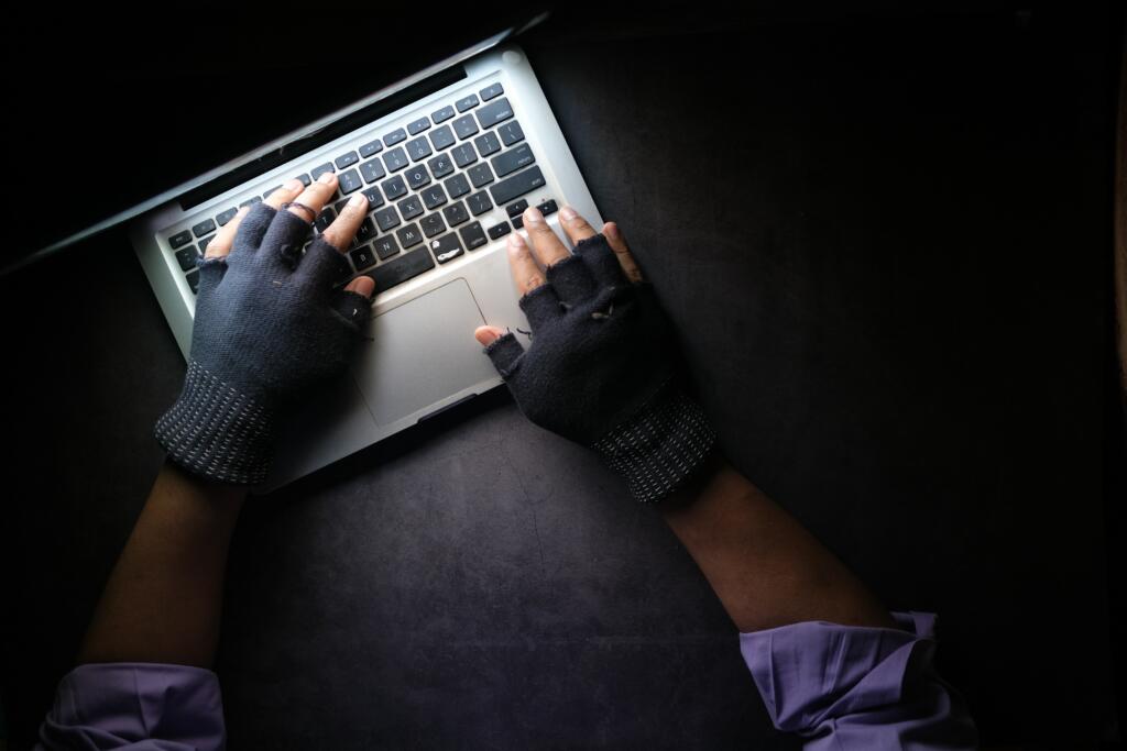 hands in gloves typing on macbook 