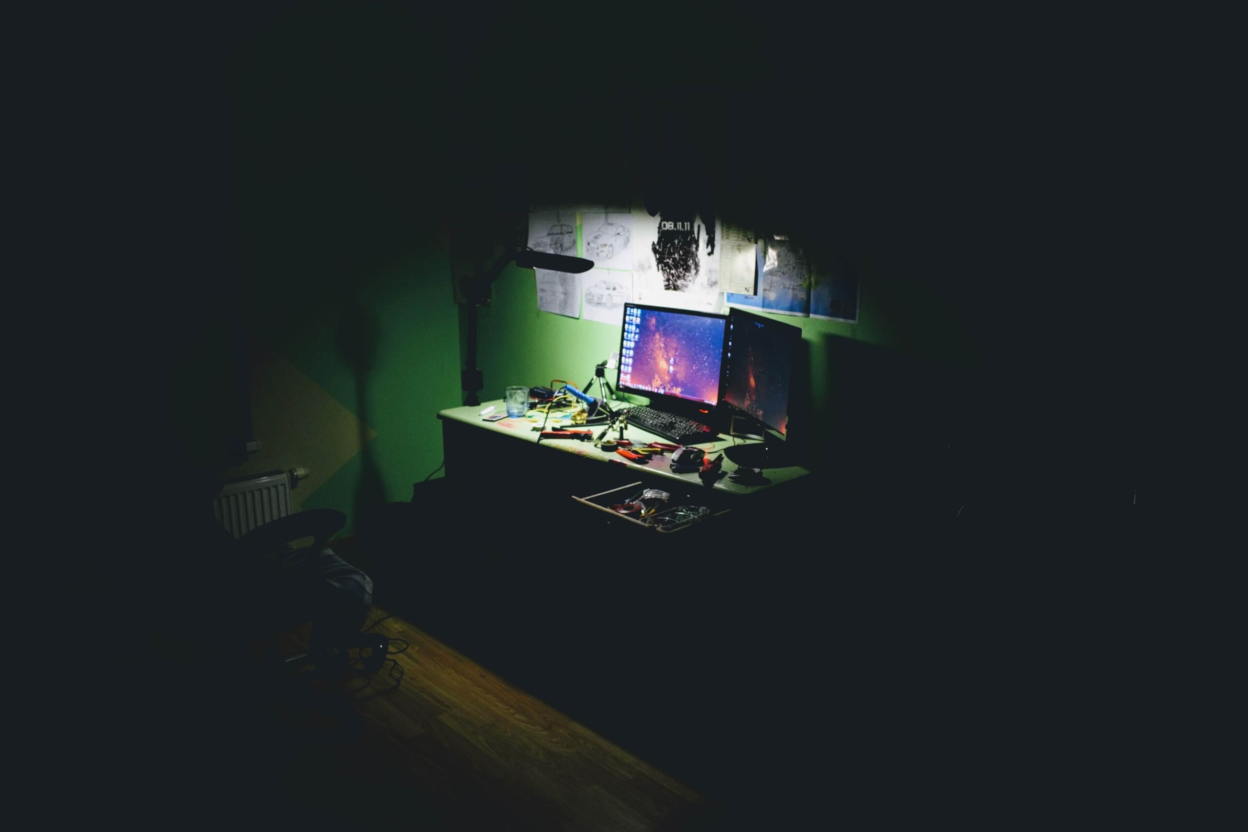 dark room desk and two computer screens 