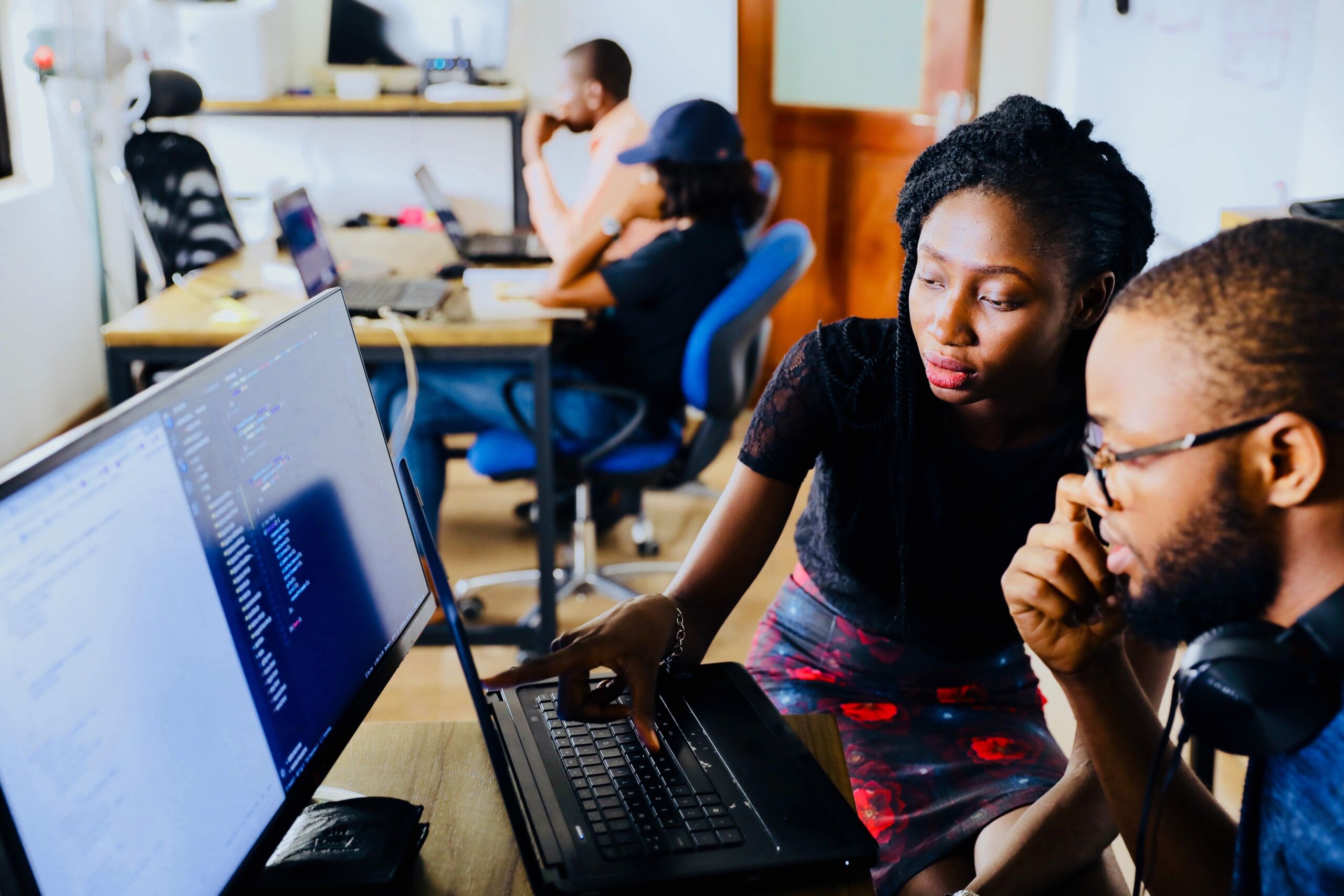 Two people working on a computer in an office.