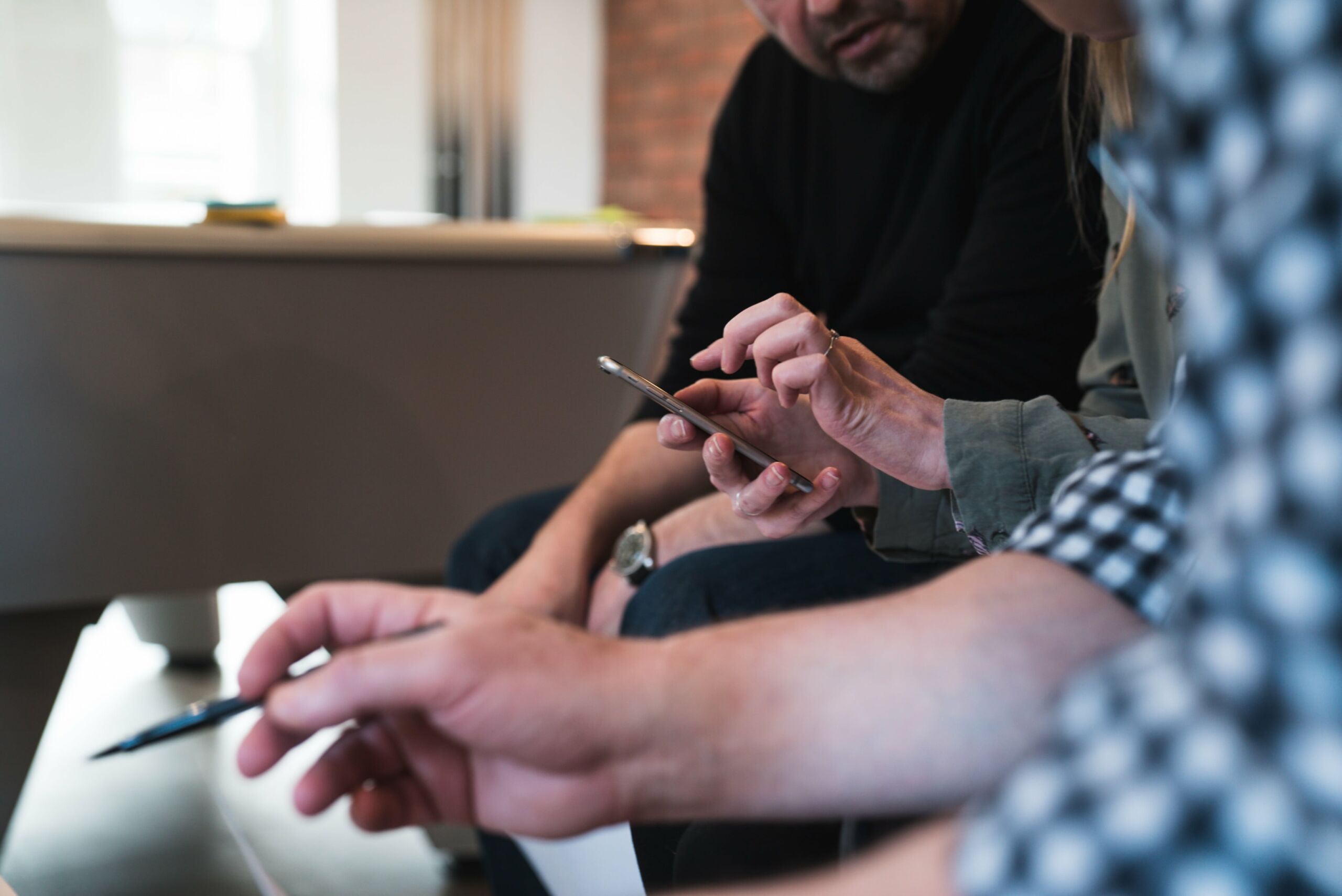A group of people engaged in bot management while occasionally glancing at their cell phones.