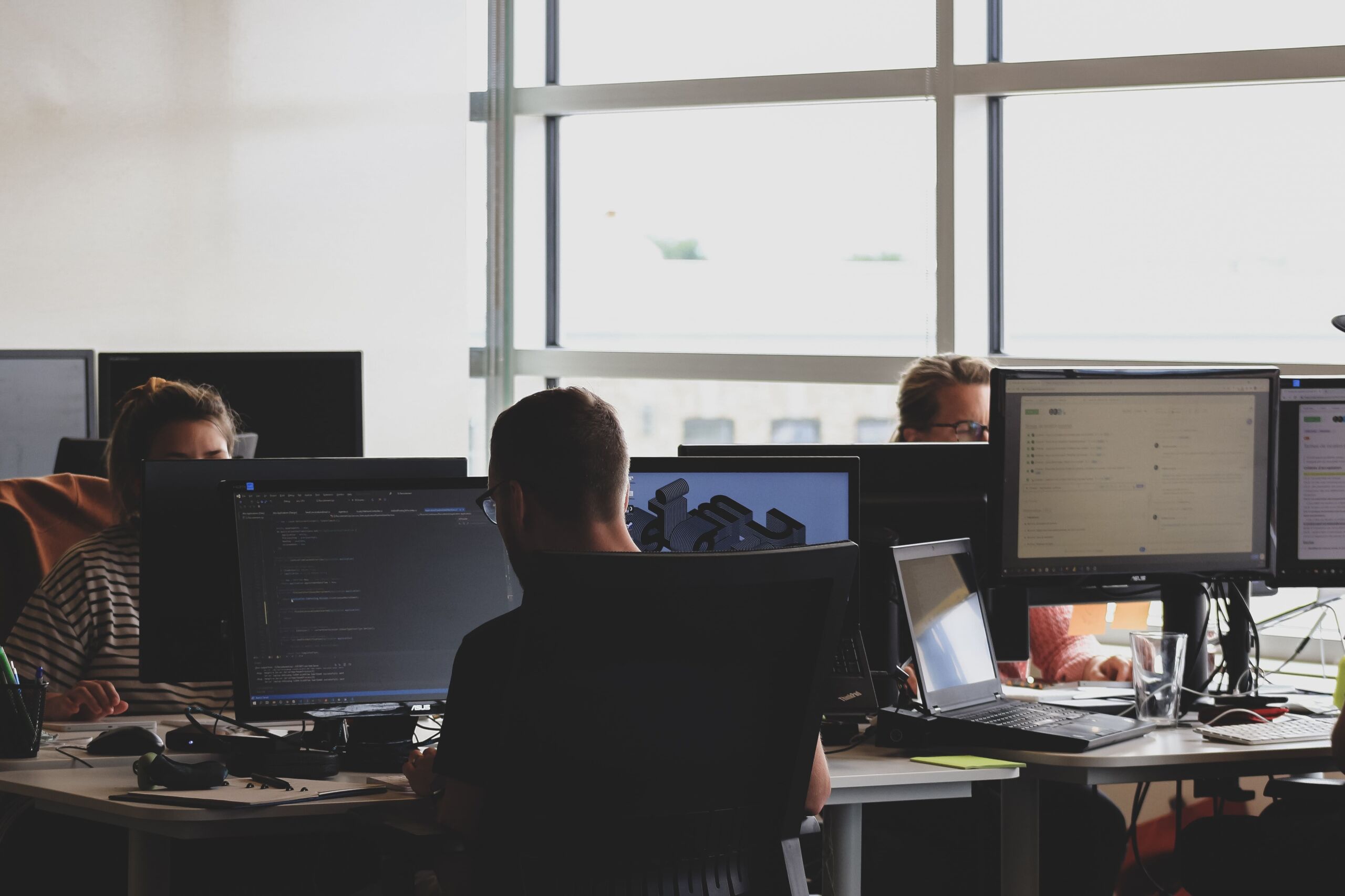 A group of people ensuring API security by working on computers in an office.