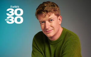 Blue and grey background with a headshot of Sam Crowther, Founder and CEO of Kasada who is posing for Forbes 30 Under 30